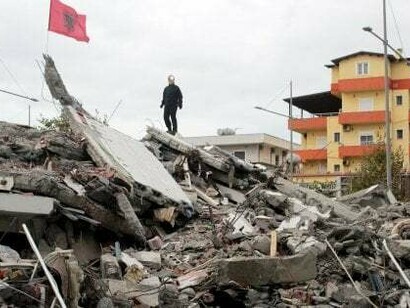 La bandiera albanese issata sopra le macerie del terremoto