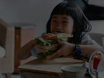 A joyous young girl delights in sipping milk and indulging in a wholesome feast of fresh, nutritious food, radiating happiness with each nourishing bite