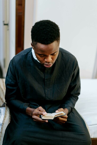 A man dressed in black holding a Bible and praying quietly