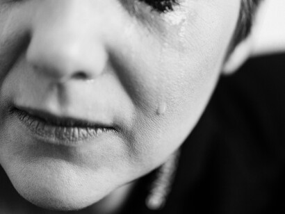 Shut eyes and wet cheeks evoke the helpless hands reaching from beneath a fallen ceiling