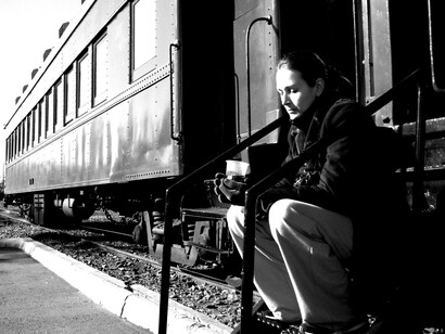Una mujer pensativa junto a un tren