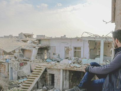 In Idlib, Idlib Governorate, Syria, a lone man looks over the war-damaged landscape, reflecting the profound destruction caused by ongoing violence