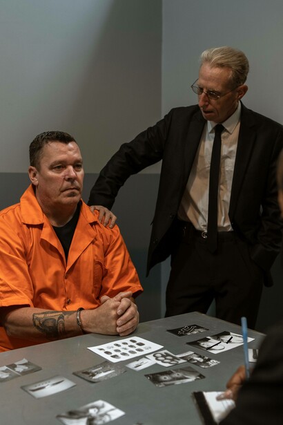 Cop puts hand on shoulder of man with an orange jump suit