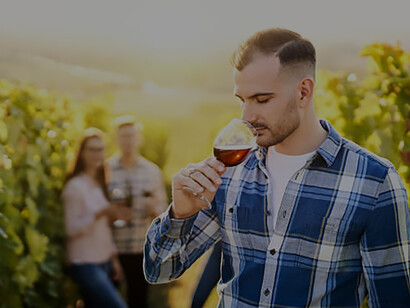 Explore the vibrant wine culture of Hungary with a compelling image of a young vintner and friends, immersing themselves in the sensory delight of tasting organic bio red wine amidst the scenic beauty of the vineyard