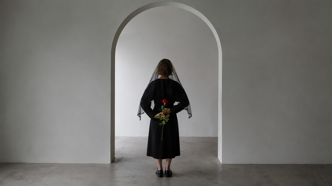 A woman in a black dress holds a red rose, symbolizing grief, loss, and remembrance