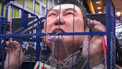 Protesters march toward the presidential office in Seoul, carrying an effigy of President Yoon Suk-yeol in prison, as they rally for his impeachment