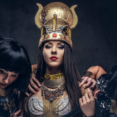 Surrounded by attendants, she exudes authority in her majestic headdress—just like the queens who shaped fashion history