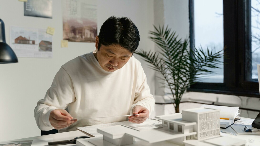 An architect refines a physical scale model, bringing traditional craftsmanship with digital design