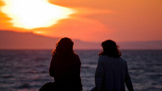Dos amigas junto al mar contemplando la puesta de sol