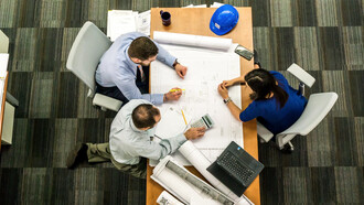 Una stanza vista dall'alto con degli architetti riuniti intorno ad un tavolo mentre lavorano