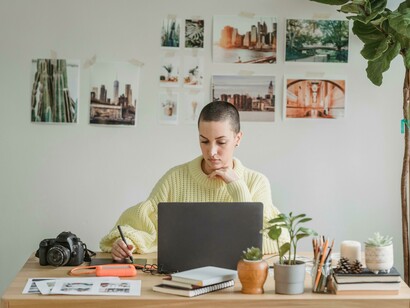 A woman works on her laptop while sketching on a drawing tablet, capturing the flow of a graphic designer at work