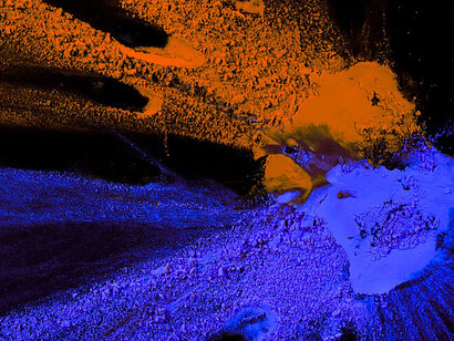 An overhead view of orange and blue powder splattered across a dark backdrop