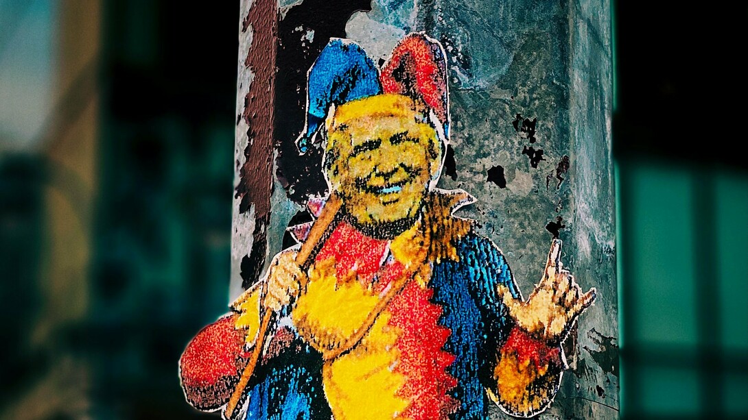The sticker's comical depiction of a jester serves as a visual rebuke against Trump's political actions