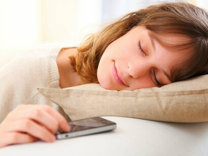 Una chica durmiendo junto a su teléfono móvil