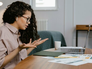 Uma mulher trabalha diante do laptop, concentrada na atividade realizada à mesa. A tela se transforma em espaço de leitura, pesquisa e produção de conhecimento, incorporando-se às práticas cotidianas de aprendizagem