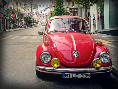 Maggiolino Volkswagen rosso parcheggiato a lato della strada