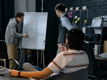 Colleagues collaborating over product ideas during a strategy session, symbolising the accelerated build-measure-learn cycle