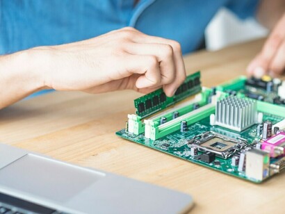 A technician fixing hardware equipment, with neuromorphic chips on a wooden workbench