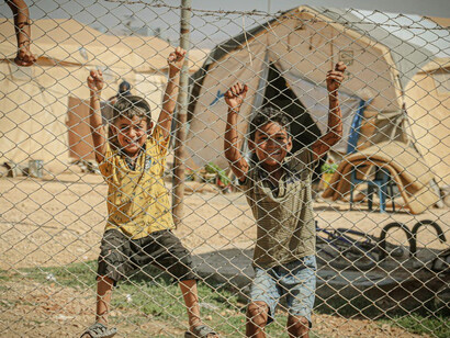 Syrian children huddling together, their expressions a poignant testament to the ongoing plight of refugees worldwide