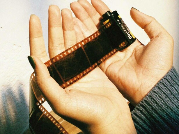 Mani attente e delicate avvolgono la pellicola cinematografica, come a proteggere storie, ricordi e sogni racchiusi in ogni fotogramma