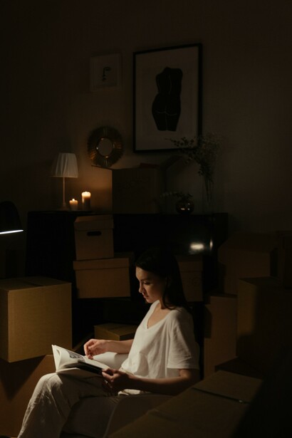 A woman sat in the dark reading a book 
