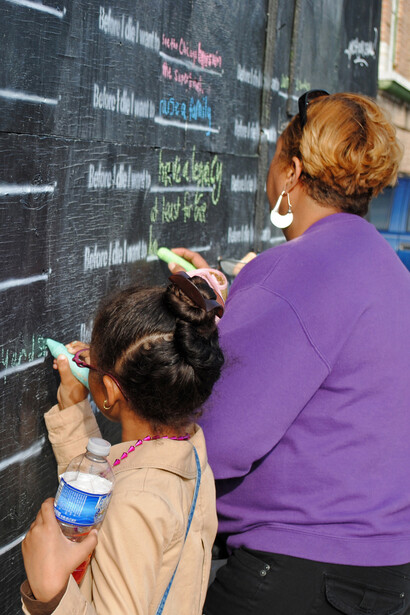 Una señora y una niña, volcando sus deseos en el mural