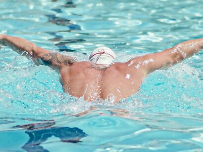 A man swimming laps across a pool, a low-impact exercise that helps improve cardiovascular help while helping with pain management