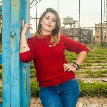 La modelo, con su suéter rojo intenso y actitud confiada, destaca de inmediato como centro emocional y visual de la fotografía