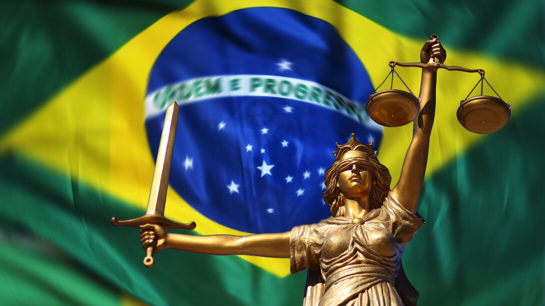 Statue of justice in front of the flag of Brazil