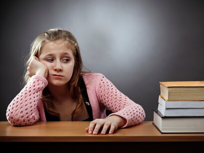 Una niña desanimada frente a sus libros