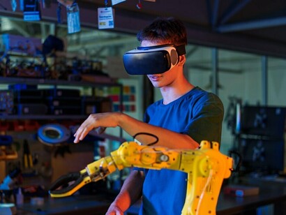A person in protective glasses operates a robot in an advanced robotics lab environment