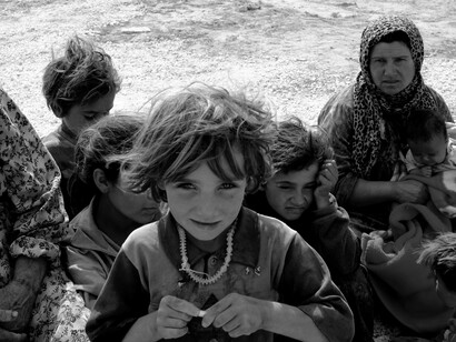A black-and-white photo of a group of people, including children of war, showing hunger and sadness