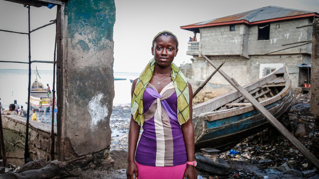 A young woman in a low-income area faces the stark reality of global economic imbalance, where the resources we have could end poverty if only we adjusted our social and political systems