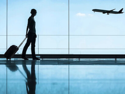 Silueta de una mujer en un aeropuerto: en la primera frontera, el viaje se transforma en un peregrinaje