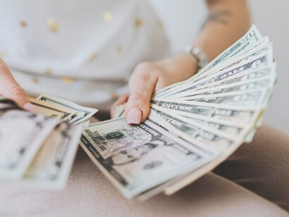 A woman showcasing her confidence as she holds a significant stack of currency