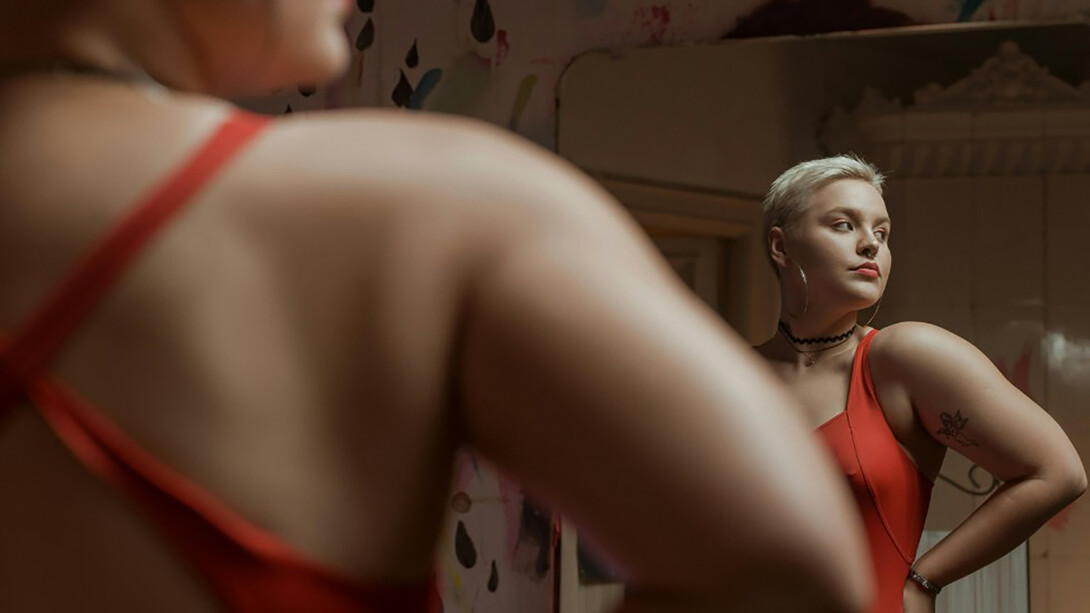 A girl looking at her reflection at the mirror in red dress