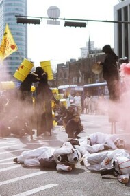 Protesters in scrub suits lie on the road surrounded by smoke during an anti-nuclear demonstration