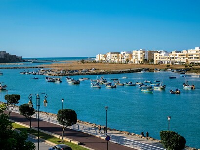 Traditional boats along the Bouregreg Marina with sleek modern buildings rising behind them, symbolising Morocco’s fusion of past and present