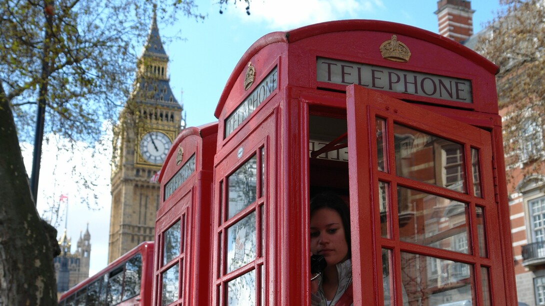 Una mujer en una de las típicas cabinas rojas de Londres con el Big Ben al fondo