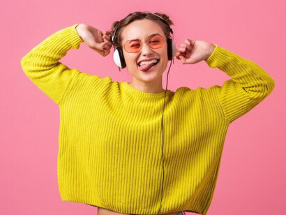 Wearing vibrant hipster fashion, a woman listens to a viral music track through her headphones