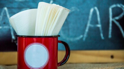 Guardanapos guardados numa caneca vermelha, à espera de uso como tantas presenças silenciosas que ocupam espaço na rotina sem realmente cumprir a função