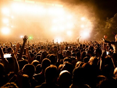 Music lovers gather by the thousands, waving their arms and singing along at a thrilling night concert