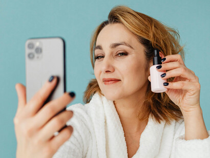 Mujer tomándose una selfie mostrando un producto de belleza