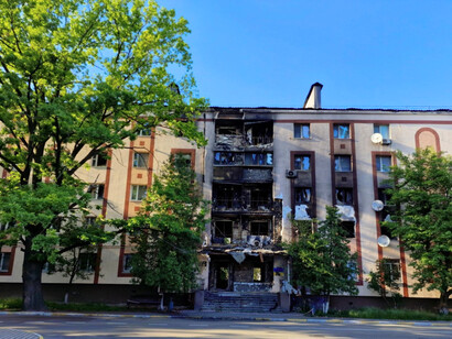 A war-ravaged urban structure in Ukraine with exposed interiors, illustrating how violence tears through everyday life
