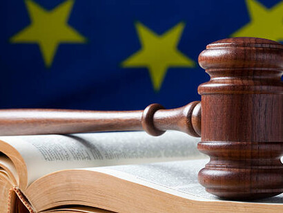 A judge’s gavel on a book with the EU flag in the background, representing the impact of EU regulations and the expanding role of European Union bureaucracy in imposing lifestyle restrictions
