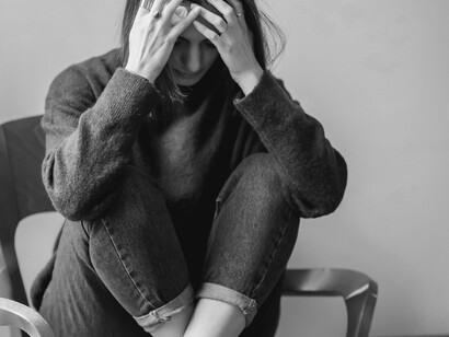 A woman hiding her face with her hands as she realizes the severity of her failure
