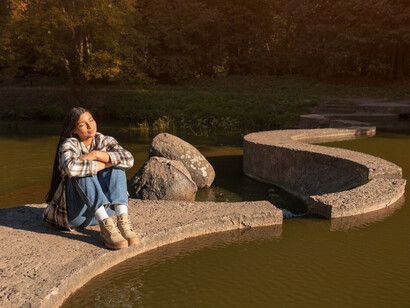 A smiling woman relaxing in nature, embodying peace and experiencing spiritual awakening