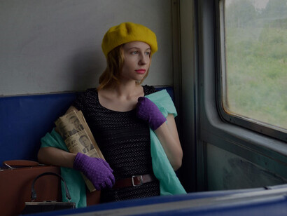 Delve into the captivating image of a composed young lady with a suitcase, absorbed in a Russian newspaper, as she embarks on a train voyage through the scenic landscapes of Russia, evoking wanderlust and adventure