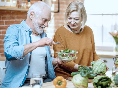 Pareja de adultos mayores prepara una ensalada. La nueva visión del envejecimiento, también postula la necesidad de perderle el miedo al propio proceso de envejecimiento