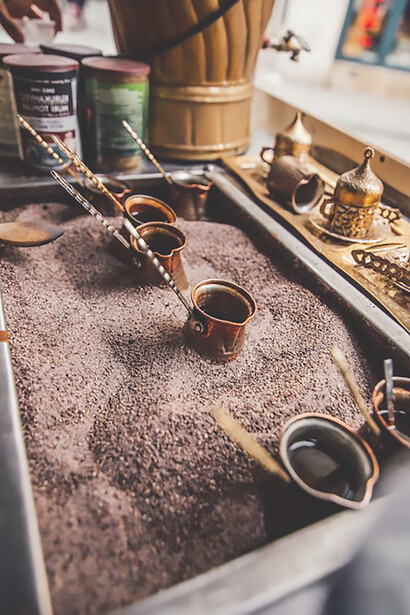 Transport yourself with a captivating image of Turkish coffee brewing in a copper pot on the sand